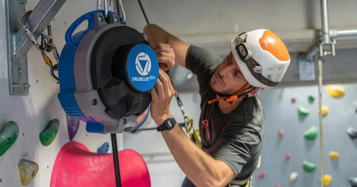 TRUBLUE auto belay being detached from a climbing wall for annual service